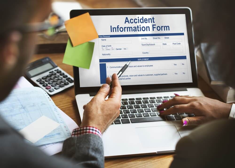 An accident report displayed on a laptop with two people.