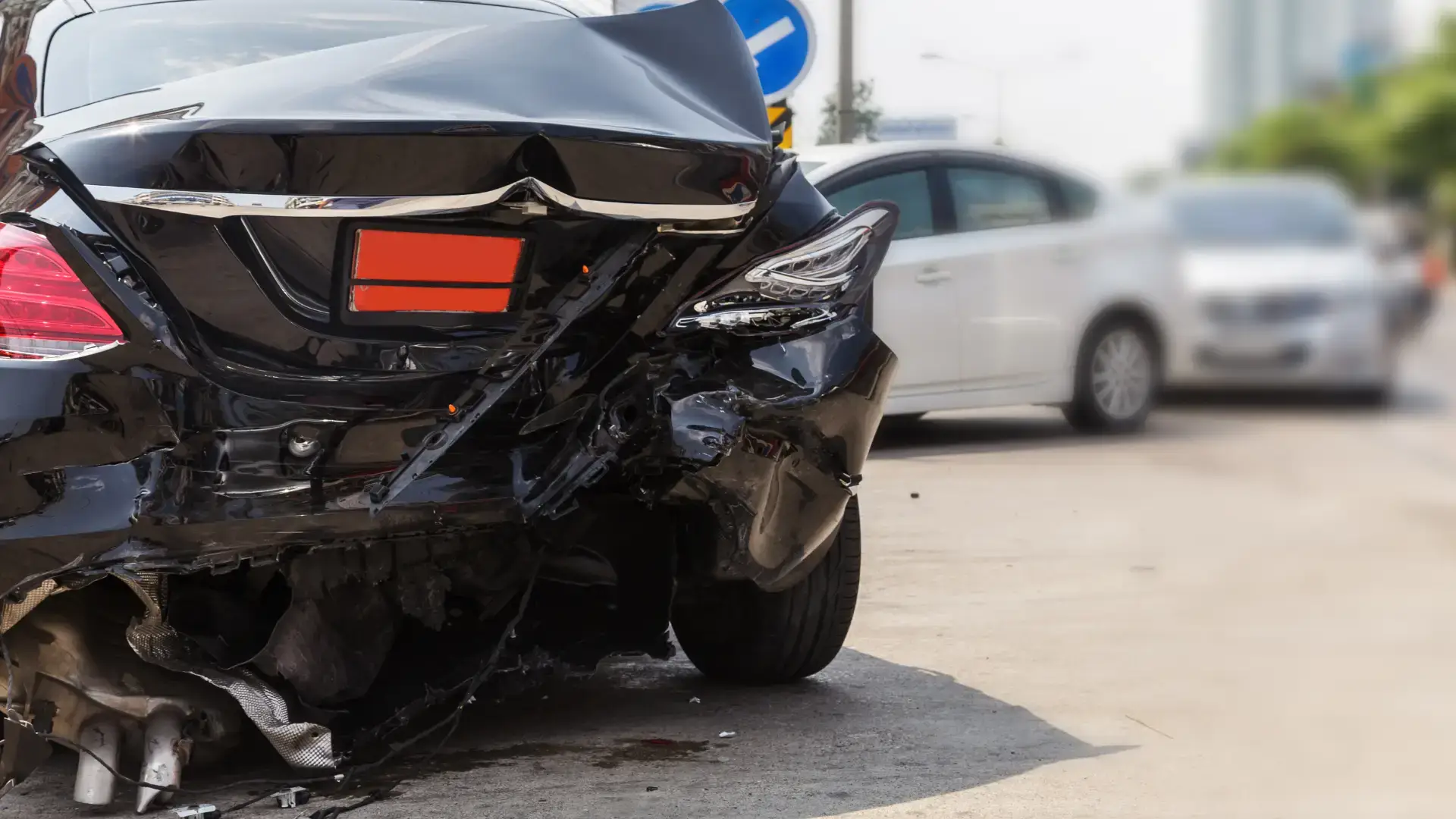 Close-up of a black car with severe rear-end damage, likely from an accident.