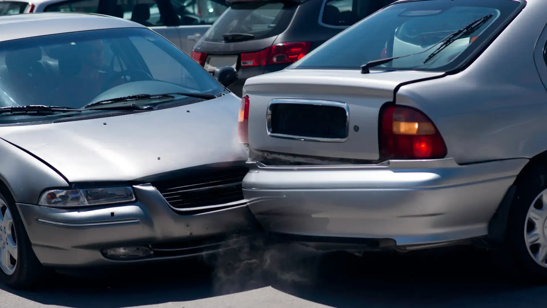 A rear-end collision between two silver cars in a parking lot.