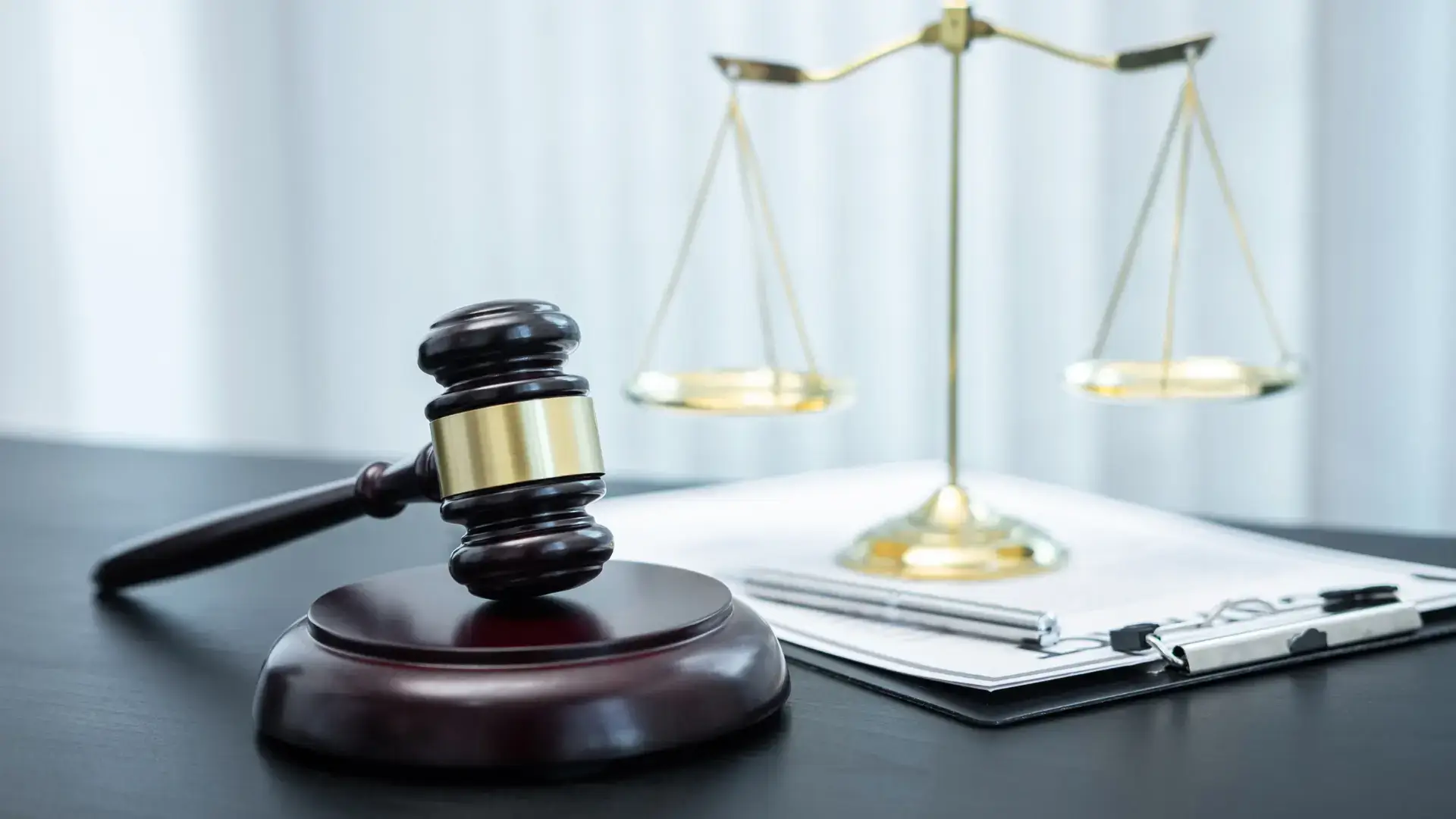 A gavel and scales of justice on a desk with legal documents and a pen.