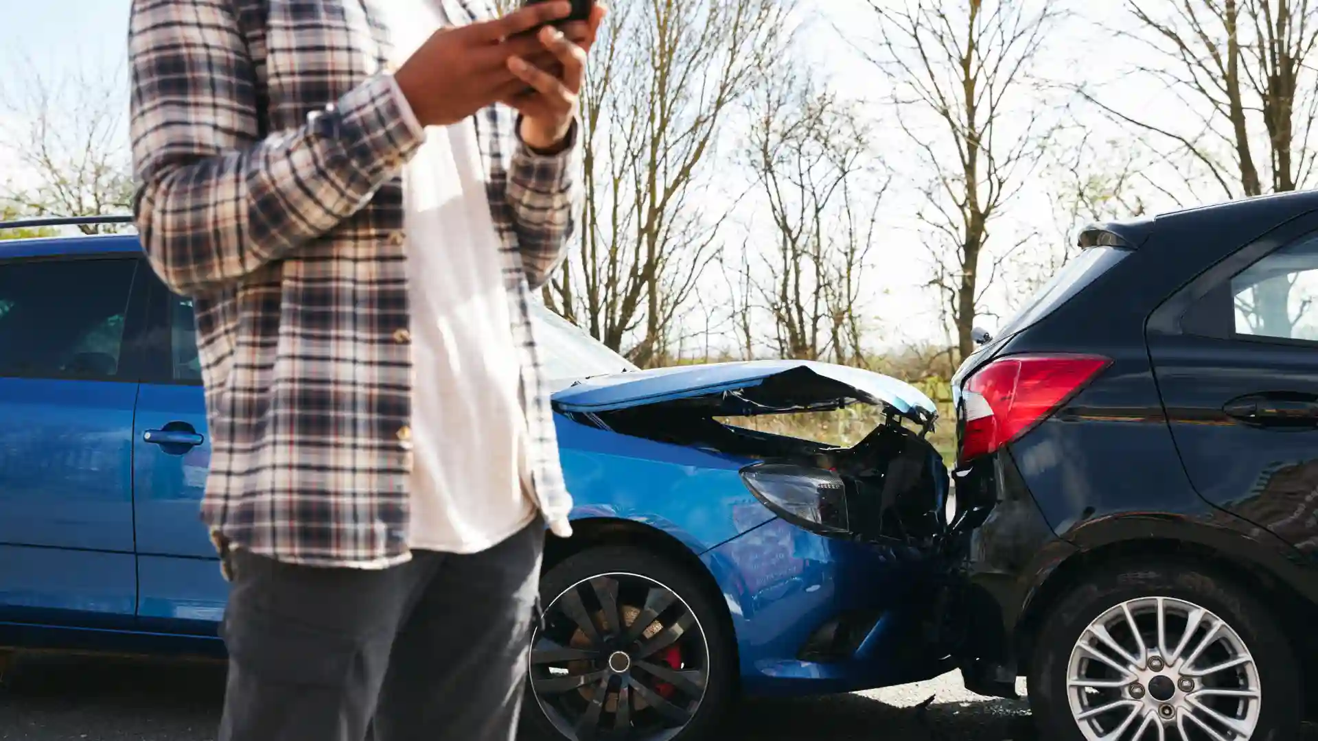 A man on his phone near a rear-end car accident.