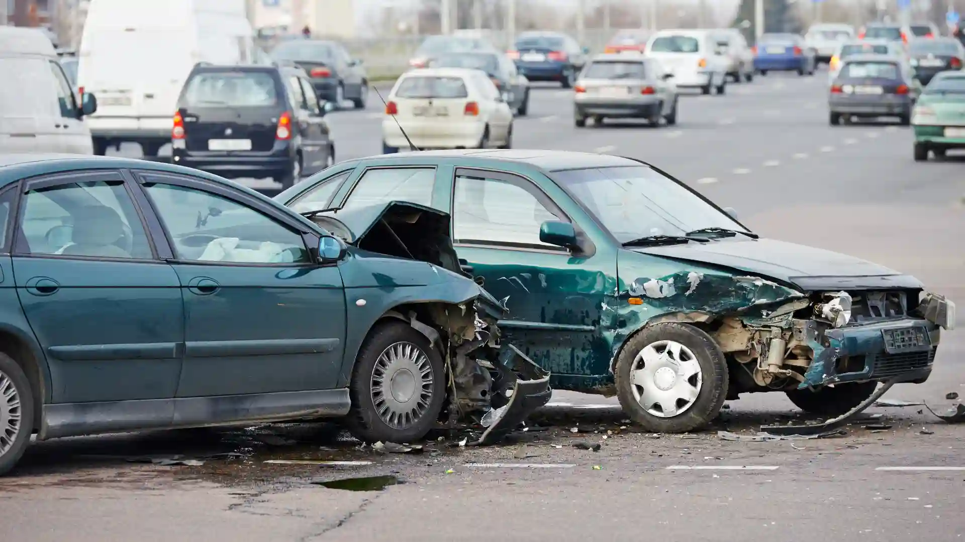 Two damaged cars after a collision on a busy road.