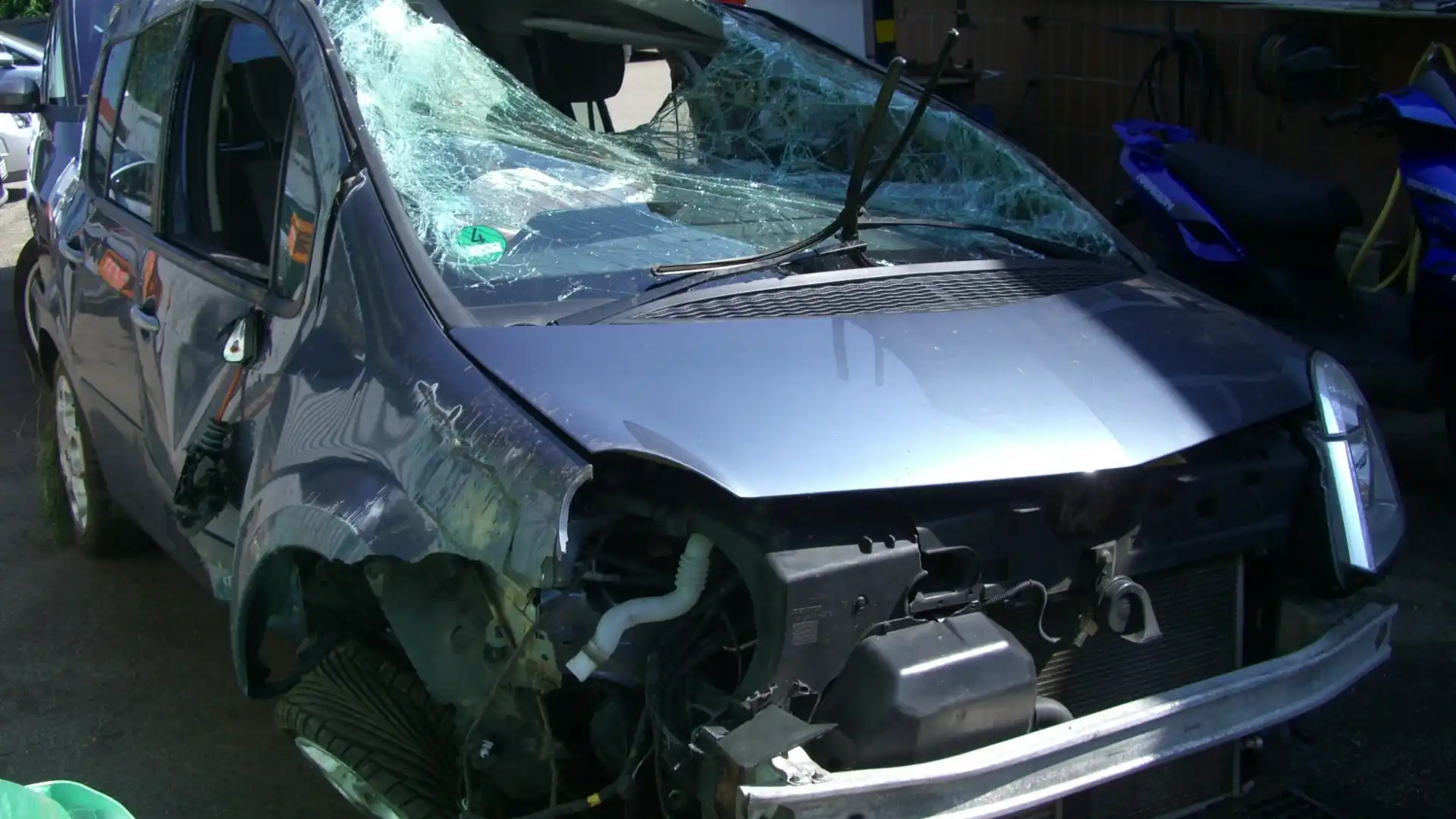 A heavily damaged car with a shattered windshield.