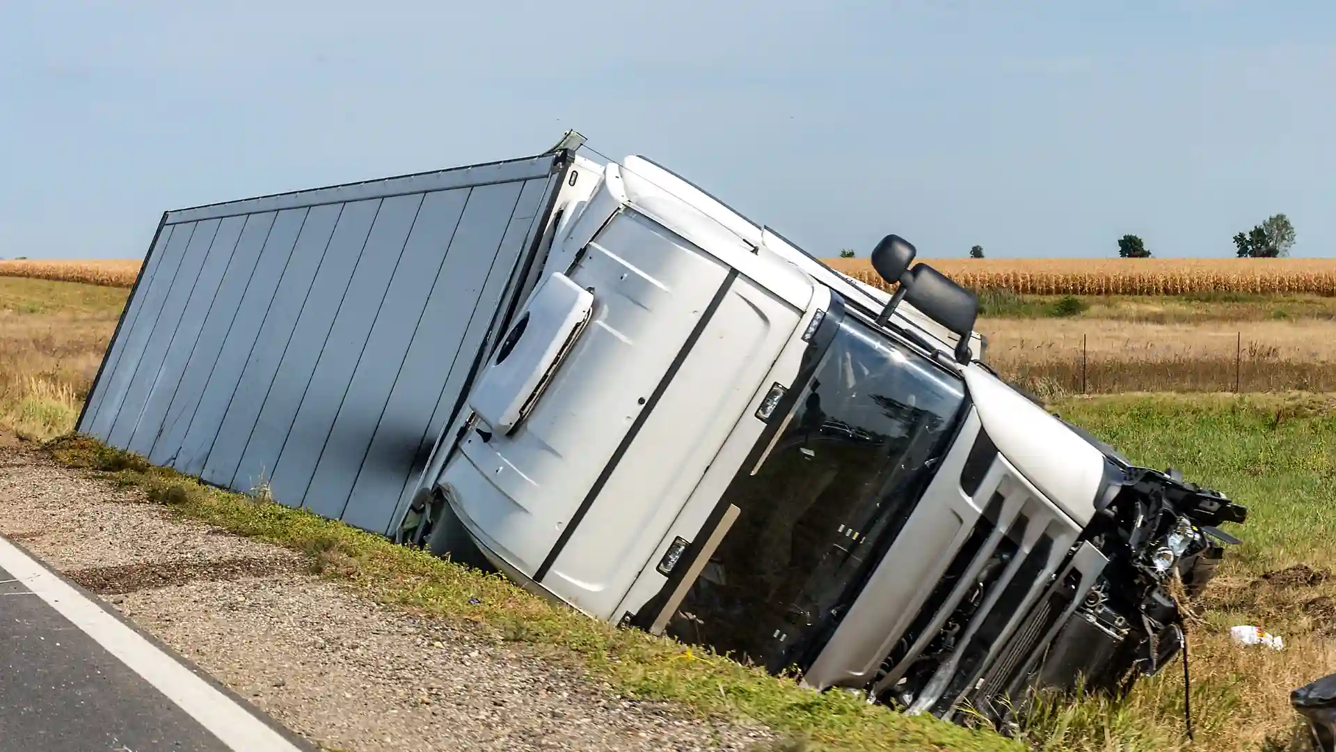 An overturned truck on the side of the road with visible damage.